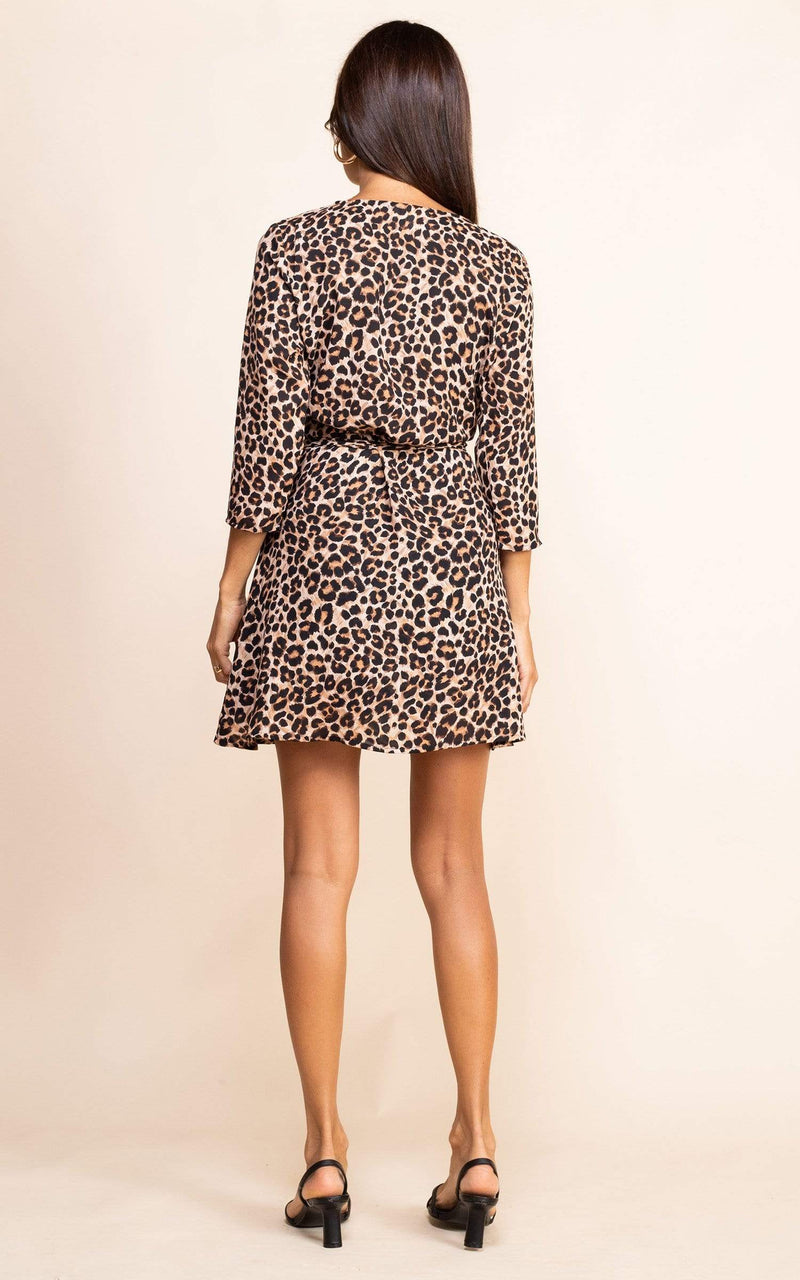 Dancing Leopard model faces backward wearing the Teagan Dress in Leopard print with heeled sandals