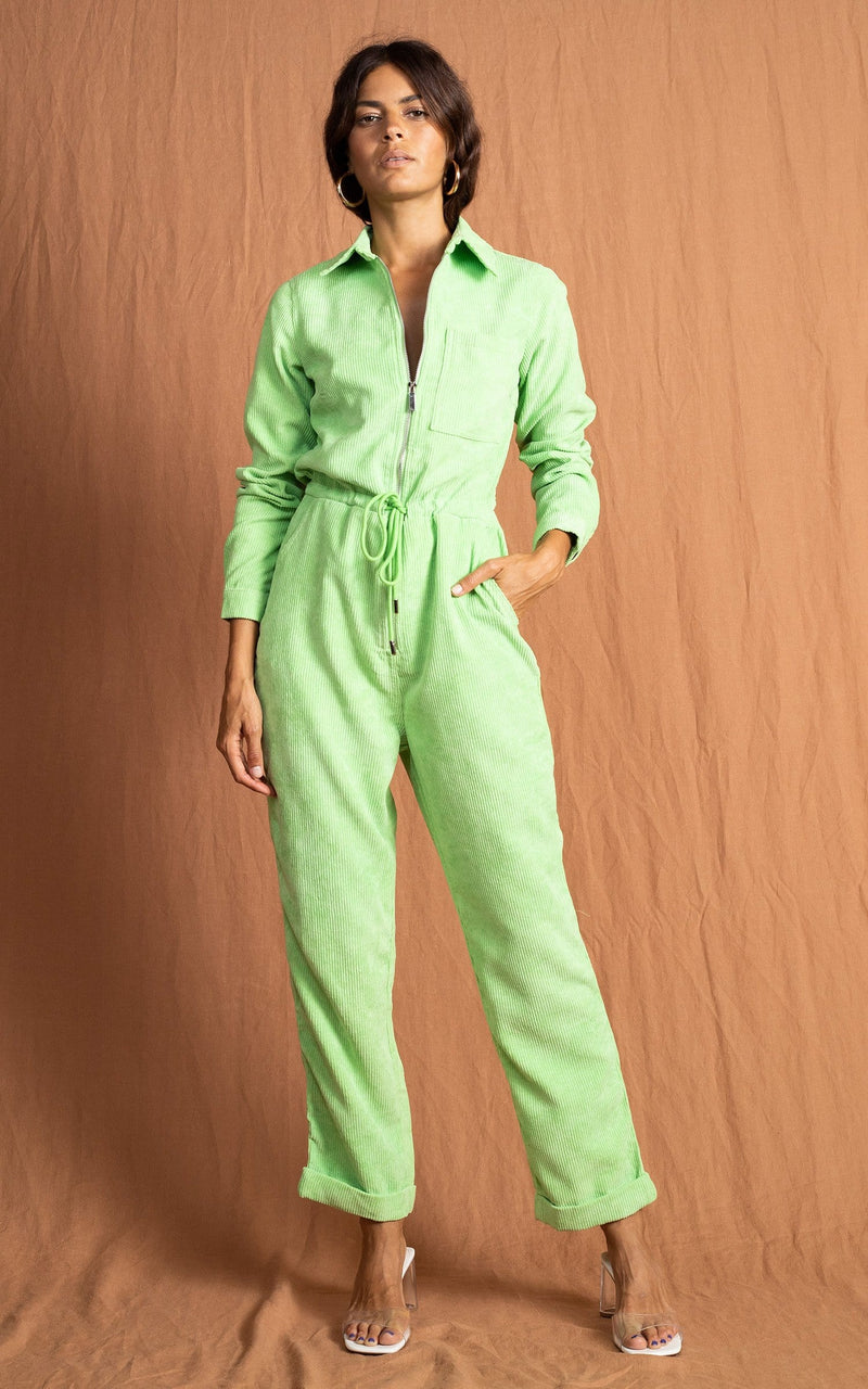 Dancing leopard model standing forwards with hand in pocket wearing blaze boiler suit in lime with white heels