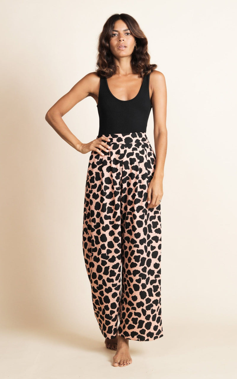 Dancing Leopard model standing with one hand on hip front to camera wearing wide leg trousers in black and beige polka dot print and black bodysuit