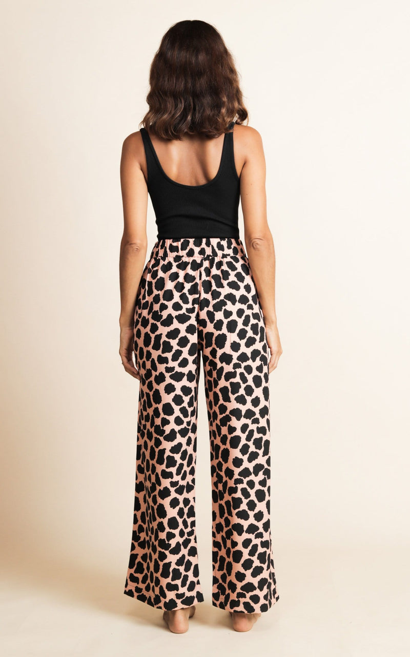 Dancing Leopard model standing back to camera wearing wide leg trousers in black and beige polka dot print and black bodysuit