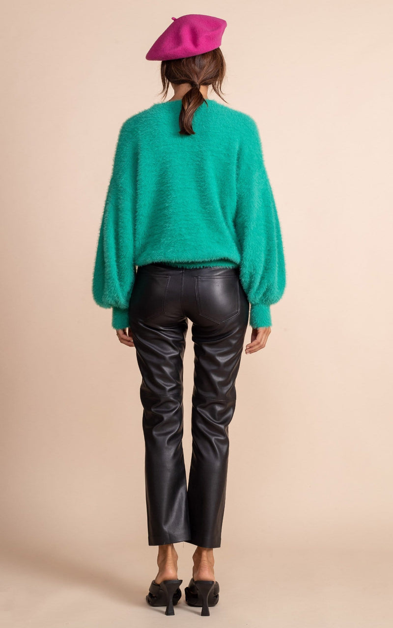 Dancing Leopard model standing with back facing the camera wearing vivid green honey jumper, black leather trousers, pink beret and black heels