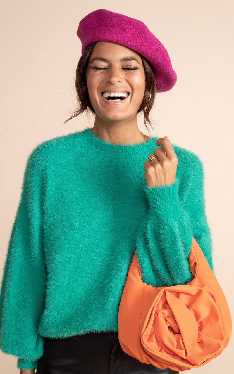 Close up of Dancing Leopard model standing wearing vivid green honey jumper, black leather trousers, pink beret and holding an orange bag