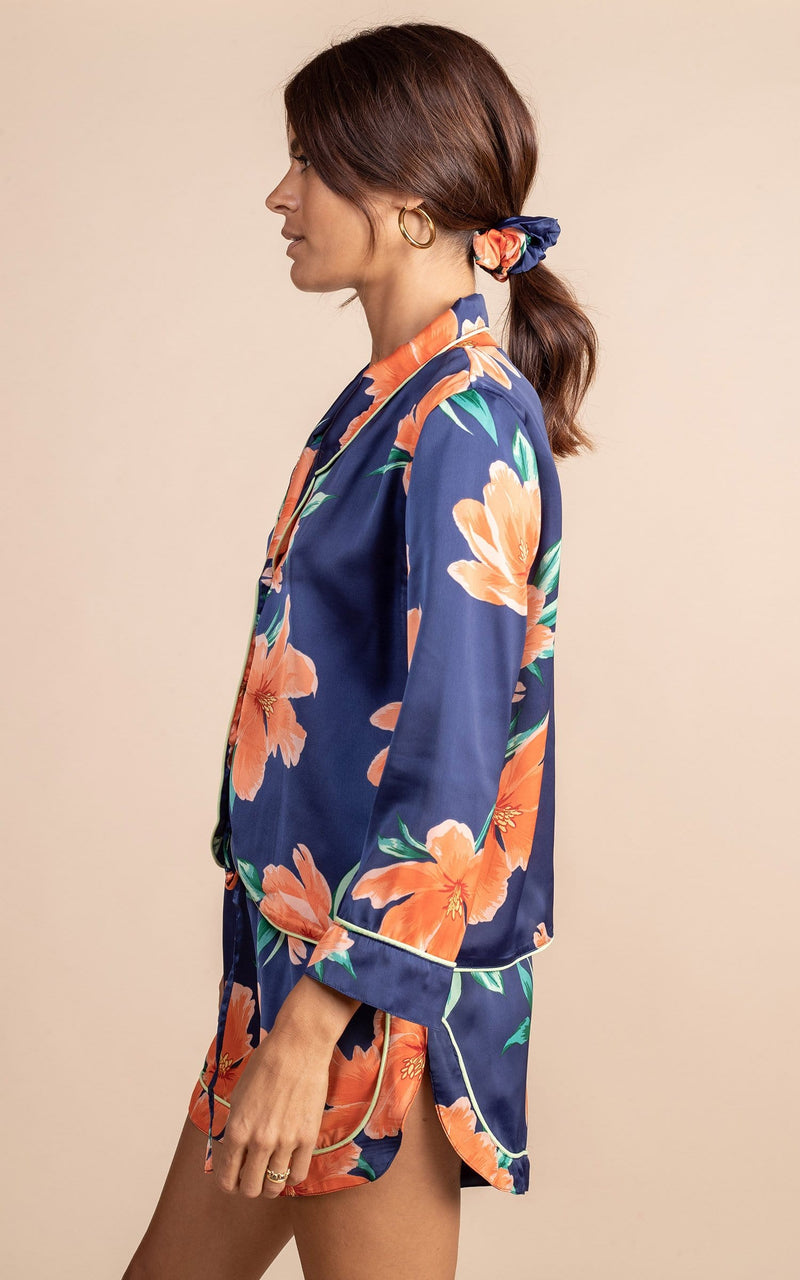 Dancing leopard model standing side  to the camera with hands by her side wearing navy blue and orange tulip  print matching pyjamas set