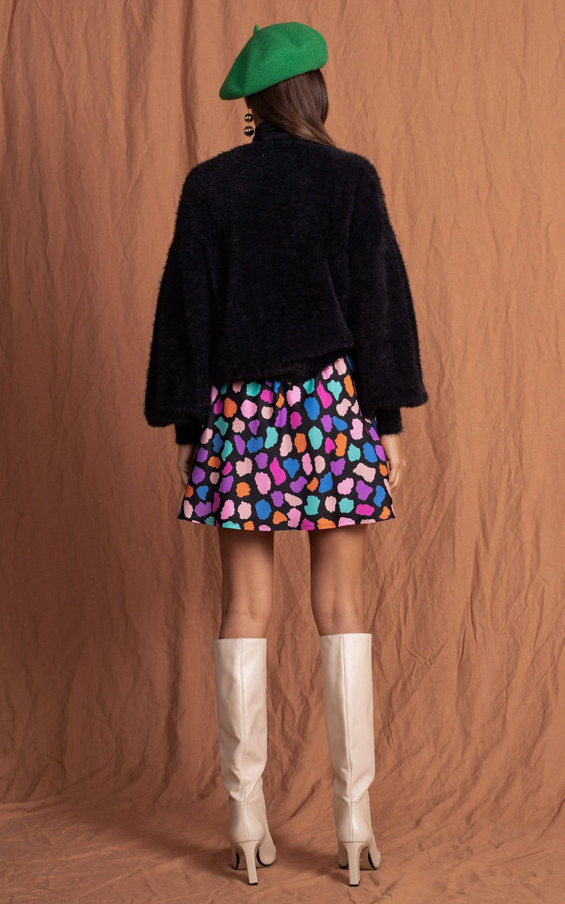 Dancing Leopard model faces backwards wearing Stevie Skirt in multi cloud with fluffy jumper, green hat and boots