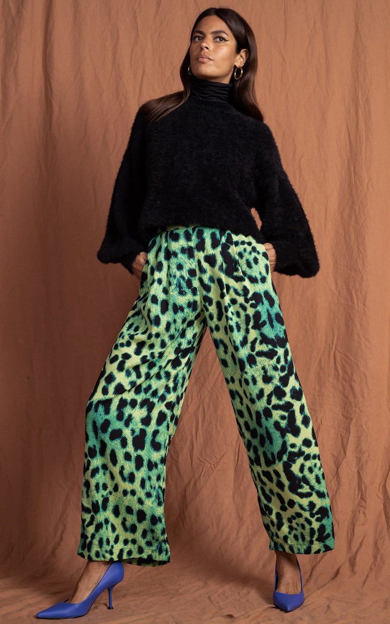 Dancing Leopard model standing forward with hands in pockets wearing lime green leopard print joey trousers with black jumper 