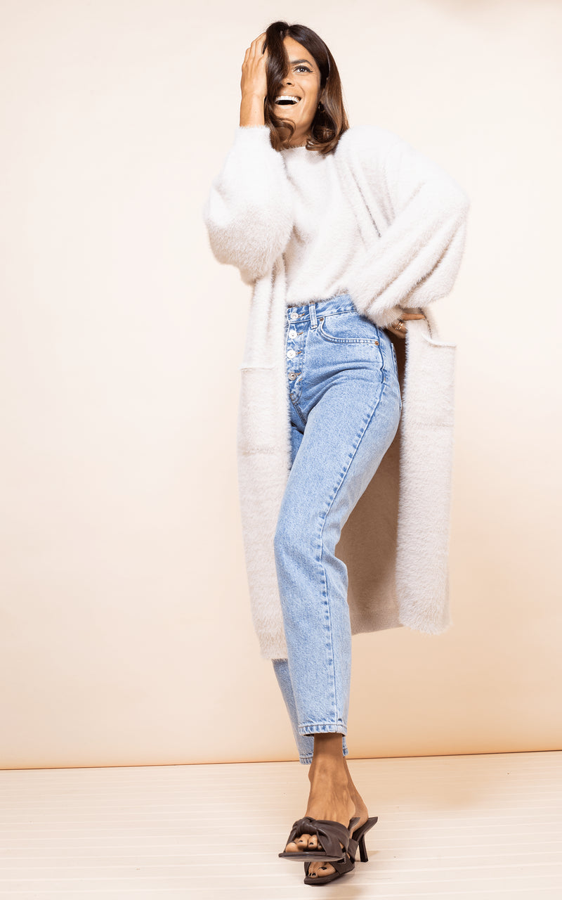 Dancing Leopard model faces forwards laughing wearing Taylor Cardigan in nude with jeans
