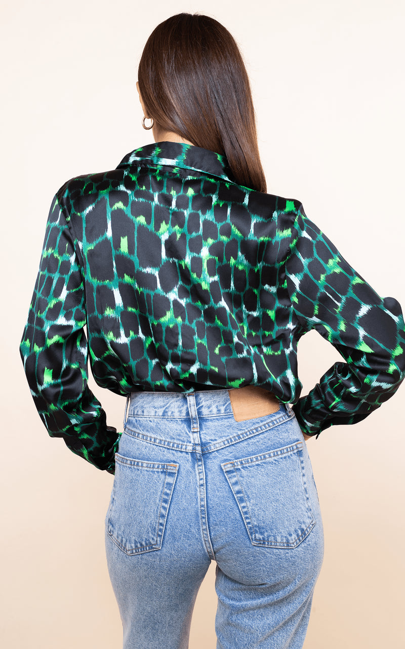 Dancing Leopard model faces backwards with hand on hip wearing San Diego Shirt in green alligator print with jeans