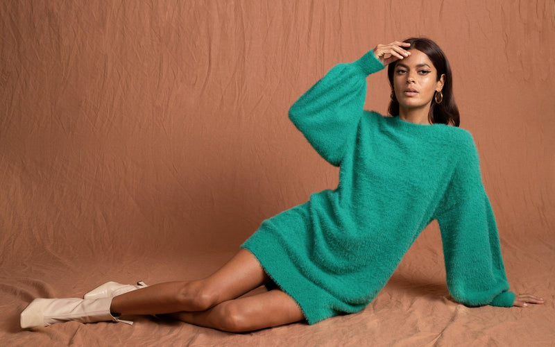 Dancing Leopard model wearing Maggie Jumper Dress in Vivid Green sat laid out on the floor with hand on head