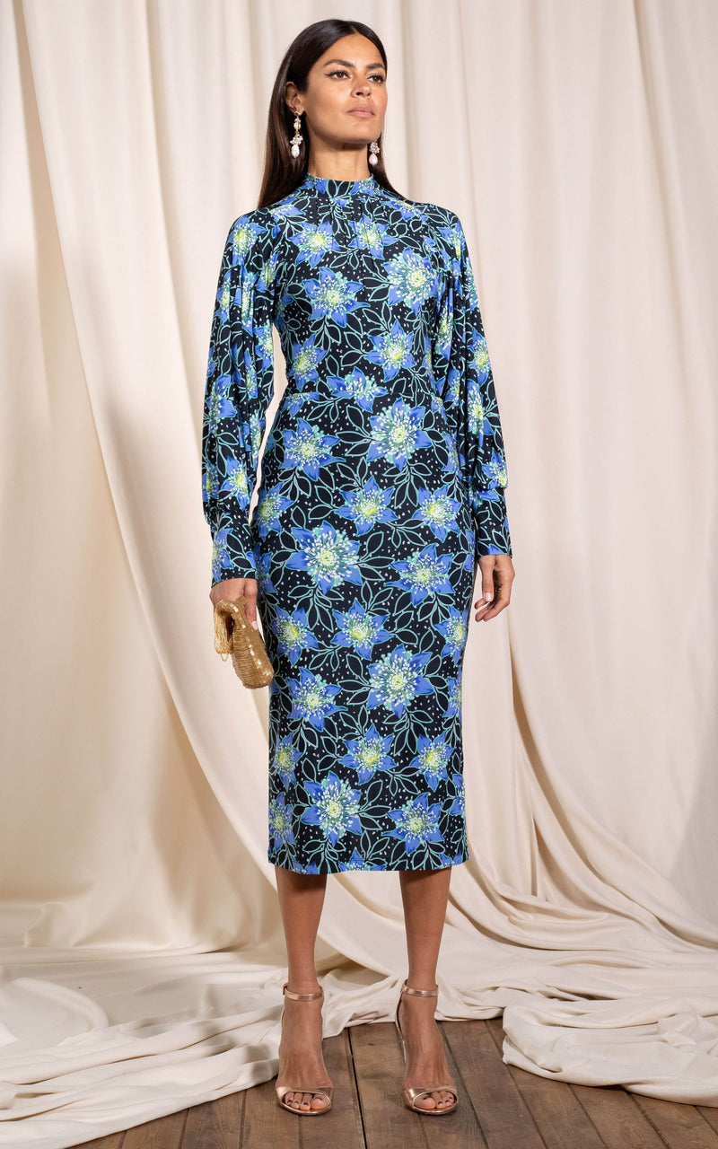 Dancing Leopard model standing slightly sideways wearing Zoe midi dress in rata blue with beaded bag