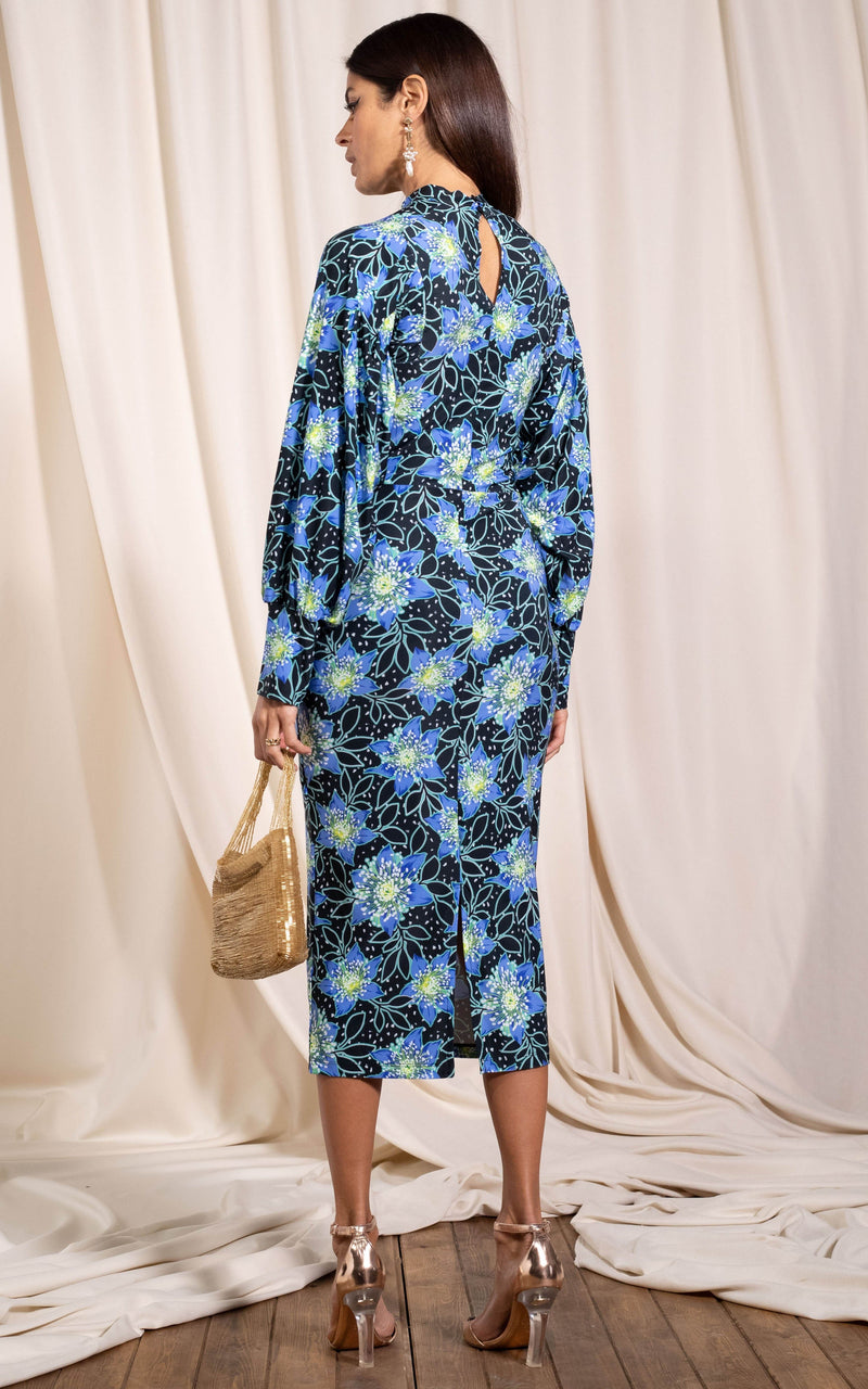Dancing Leopard model standing with back to the camera holding beaded bag wearing Zoe midi dress in rata blue