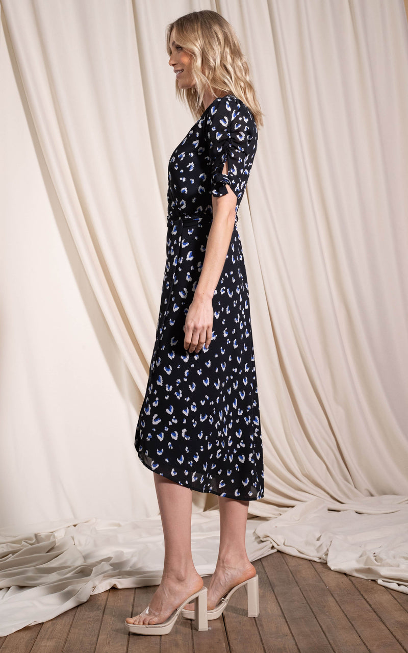 Dancing Leopard model standing sideways wearing Olivera midi dress in abstract white on black leopard