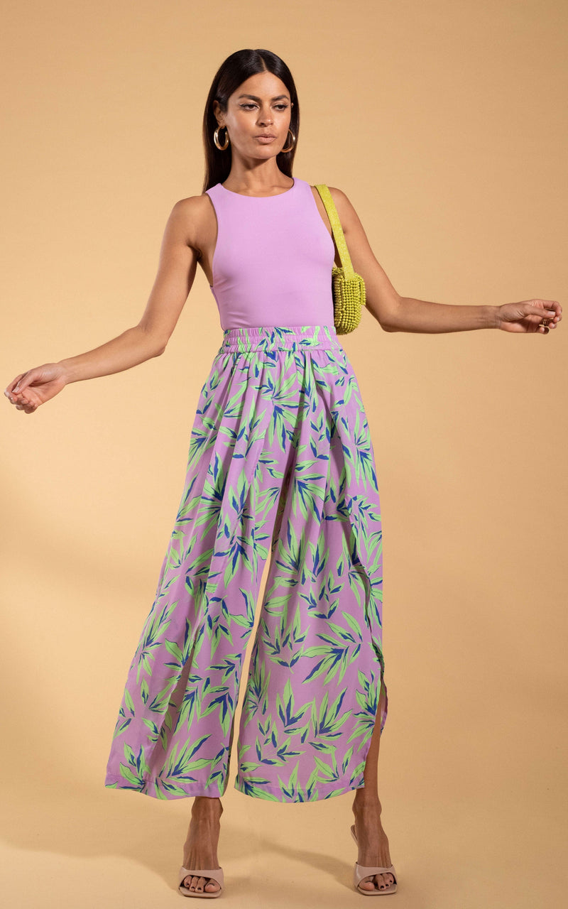 Dancing Leopard model standing with arms open wearing Kendari Split leg trousers in tropic mint on pink with yellow woven bag