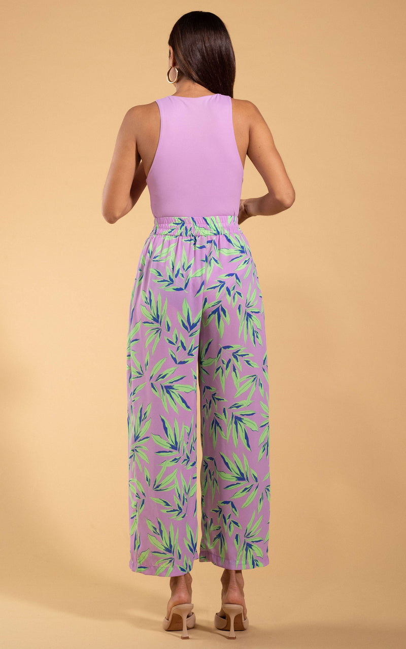 Dancing Leopard model standing with her back to the camera wearing Kendari Split leg trousers in tropic mint on pink