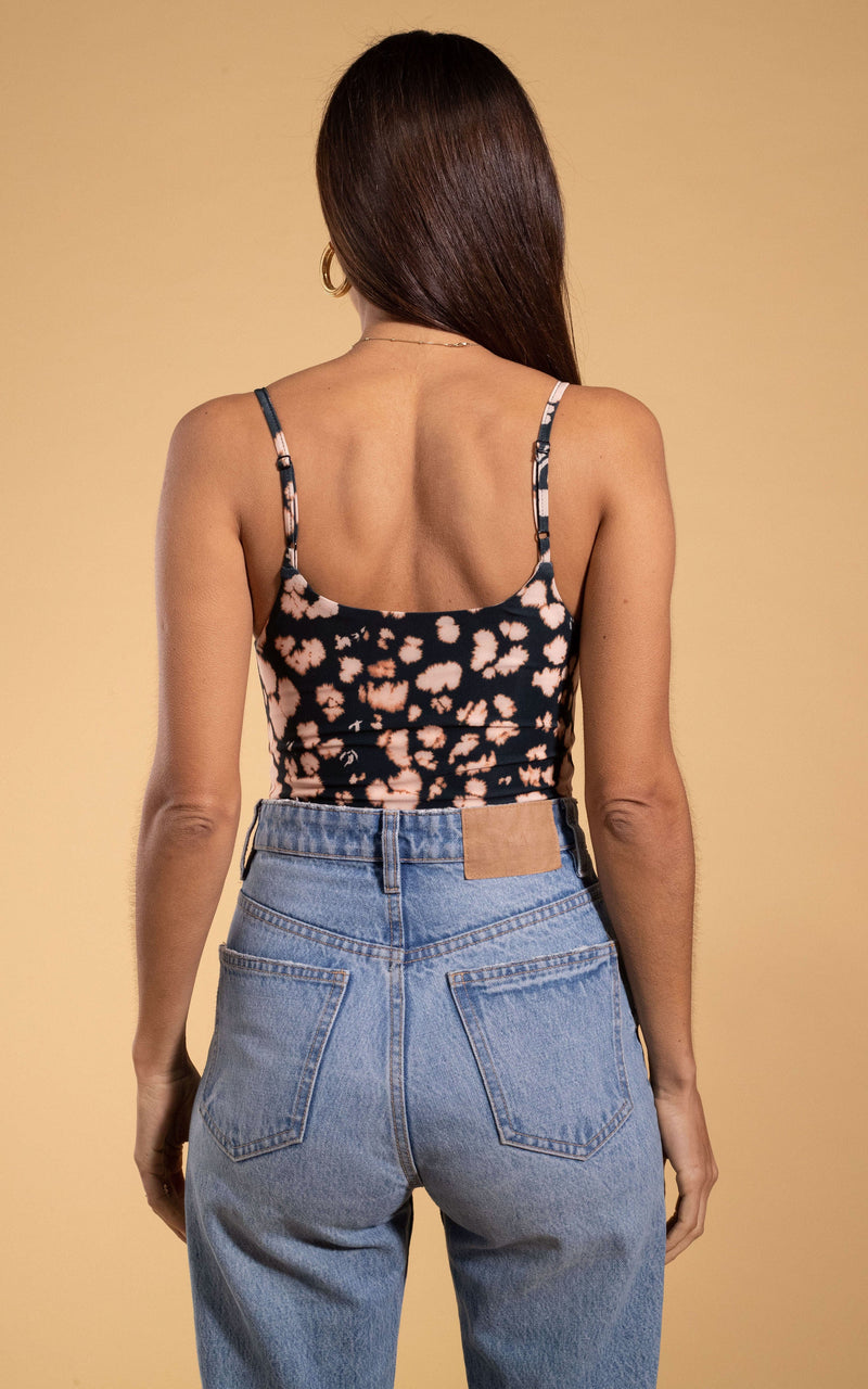 Dancing Leopard model close up facing backwards wearing Midori V-neck bodysuit in beige inky leopard with blue jeans