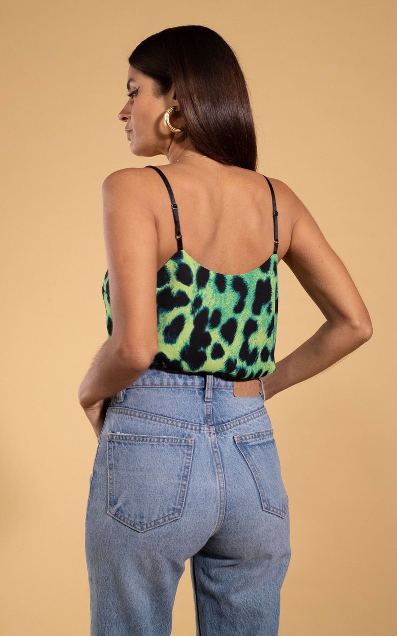 Dancing Leopard model standing with back to the camera wearing Birdie cami top in lime leopard with hands in pockets of lightwash denim jeans