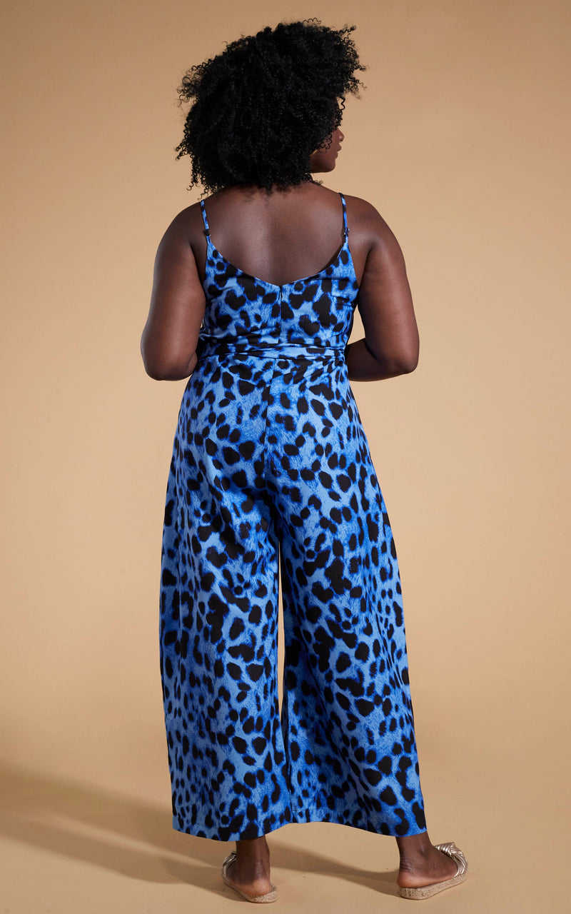 Dancing Leopard model wearing Gabriella Jumpsuit in Bright Blue Leopard facing away to reveal back of jumpsuit