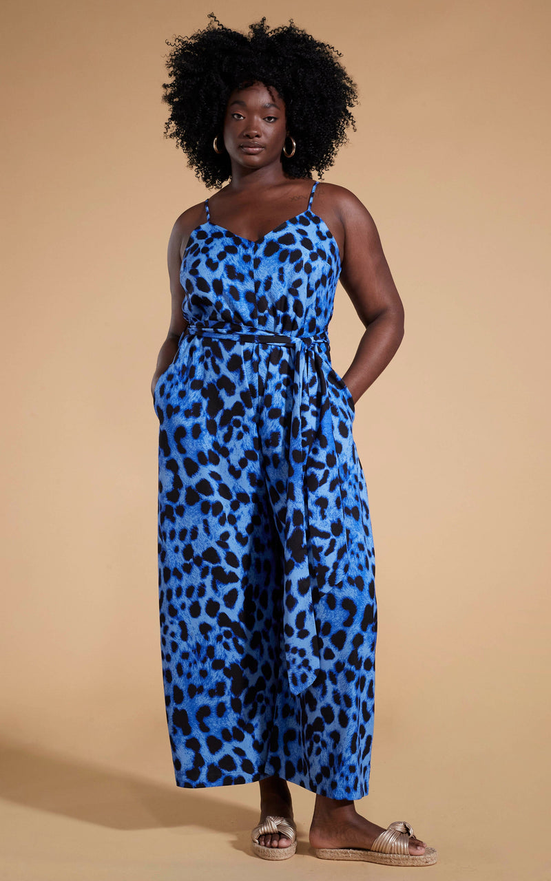 Dancing Leopard model wearing Gabriella Jumpsuit in Bright Blue Leopard posed with hands in pockets