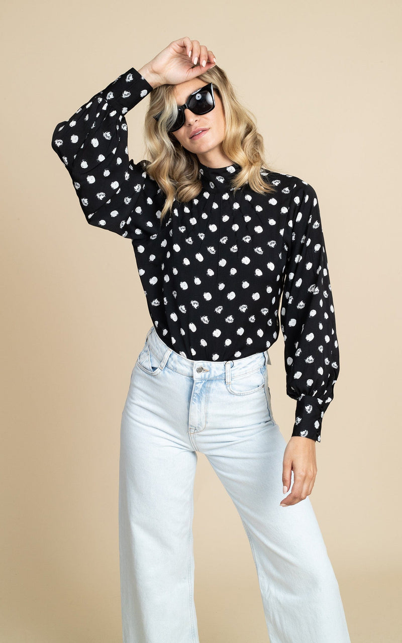 Dancing Leopard model wearing Margo Pintuck Blouse in Polka Dot posed with hand on head