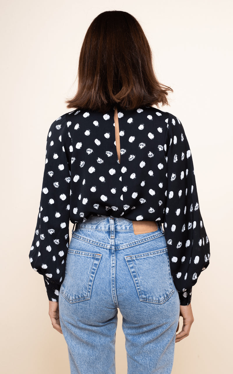 Dancing Leopard model faces backwards wearing Margo Blouse in Painted Dot with jeans