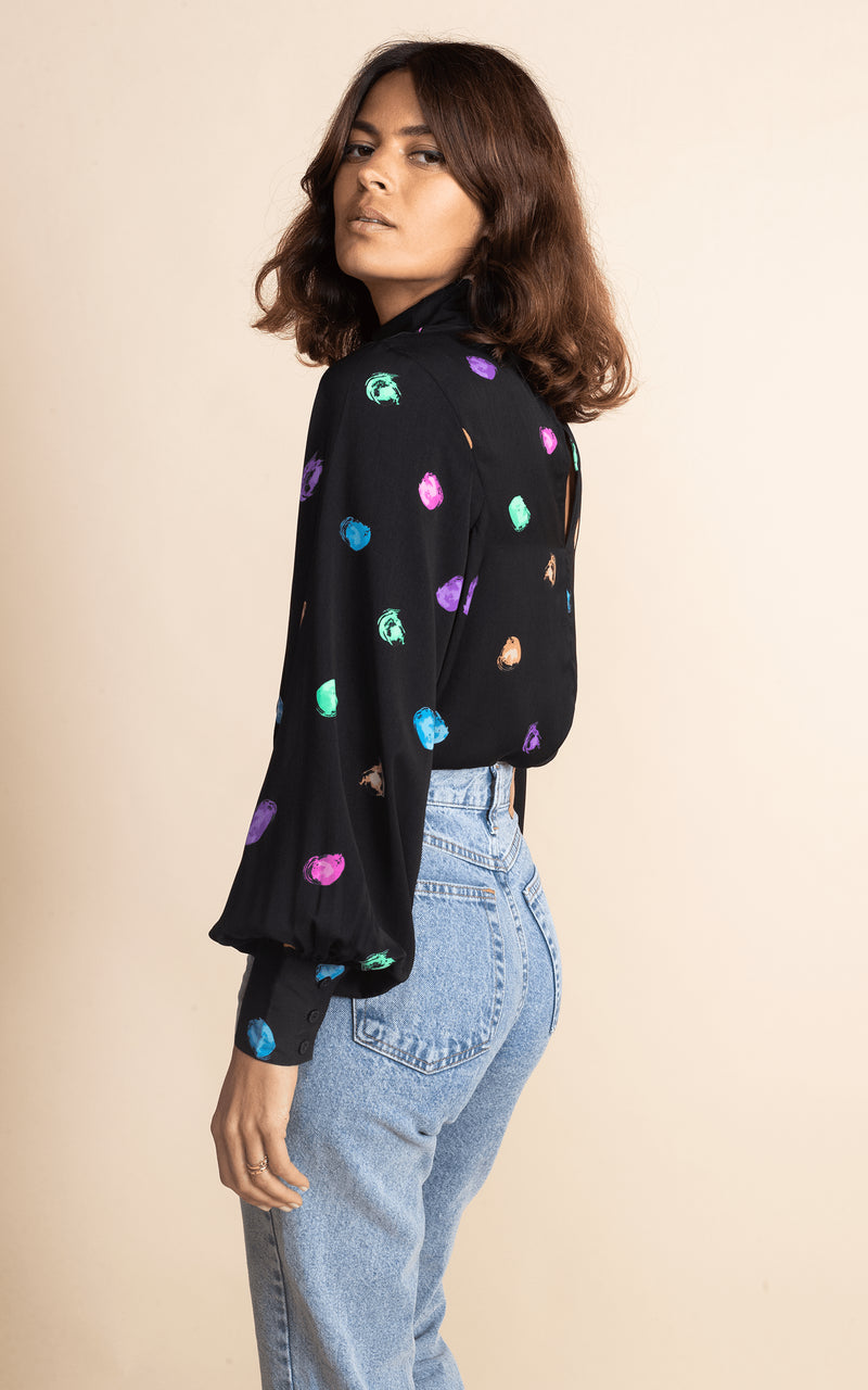 Dancing Leopard model faces side-on wearing Margo Blouse in Vintage Dots with jeans