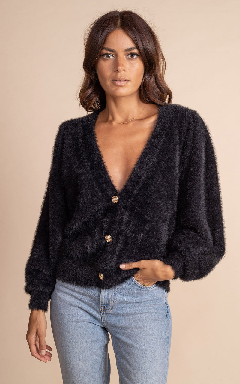 Dancing Leopard model standing with hand in pocket wearing black furry bambino cardigan and blue jeans