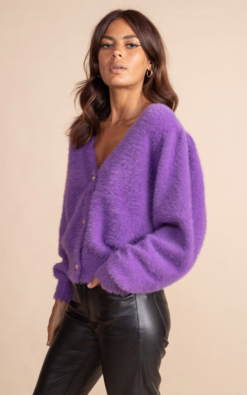 Dancing Leopard model close up standing sideways wearing fluffy bambino cardigan in indigo with black leather trousers