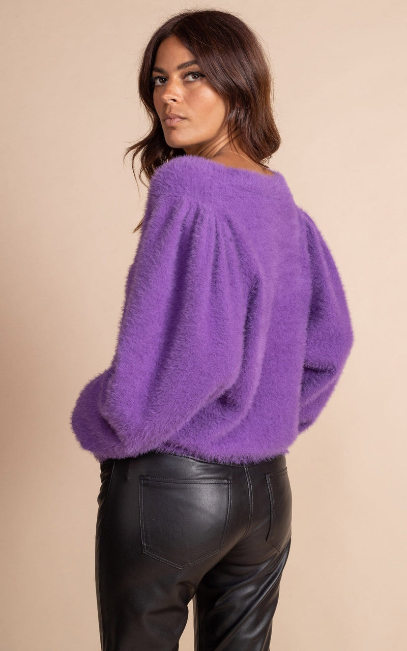 Dancing Leopard model close up standing with back facing the camera wearing fluffy bambino cardigan in indigo with black leather trousers