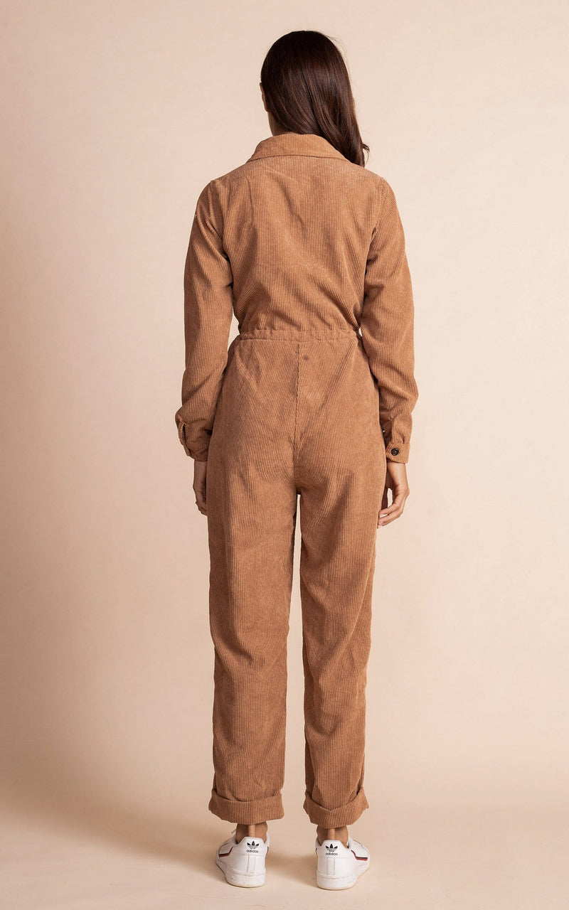Dancing leopard model standing back to the camera with tan coloured corduroy jumpsuit with white trainers