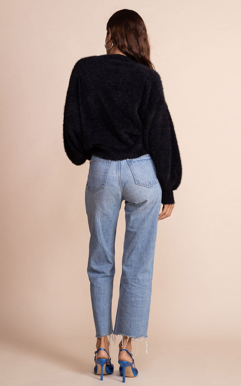 Dancing Leopard model facing back to the camera wearing black fluffy honey jumper with blue jeans