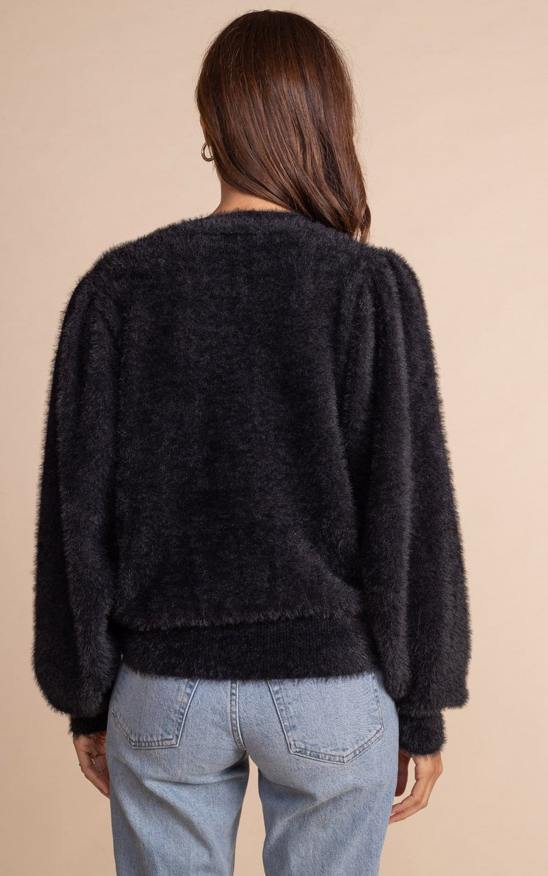 Dancing Leopard model standing with back to the camera  wearing black furry bambino cardigan and blue jeans