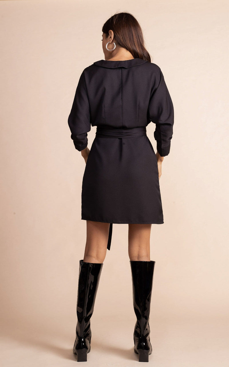 Dancing Leopard model standing with back to the camera wearing black mini wrap dress with boots