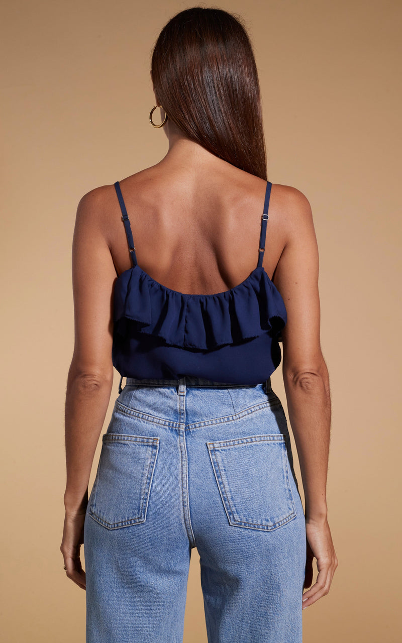 Dancing leopard model standing with back to the camera wearing blue denim jeans with susie frill cami top in navy