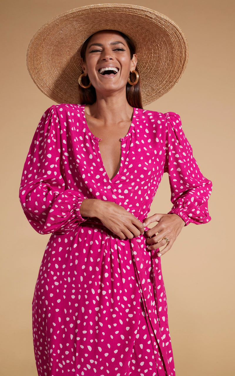 Dancing Leopard model wearing Mabel Midaxi Mock Wrap Dress in Odd Dot Pink on Magenta posed laughing with straw hat on