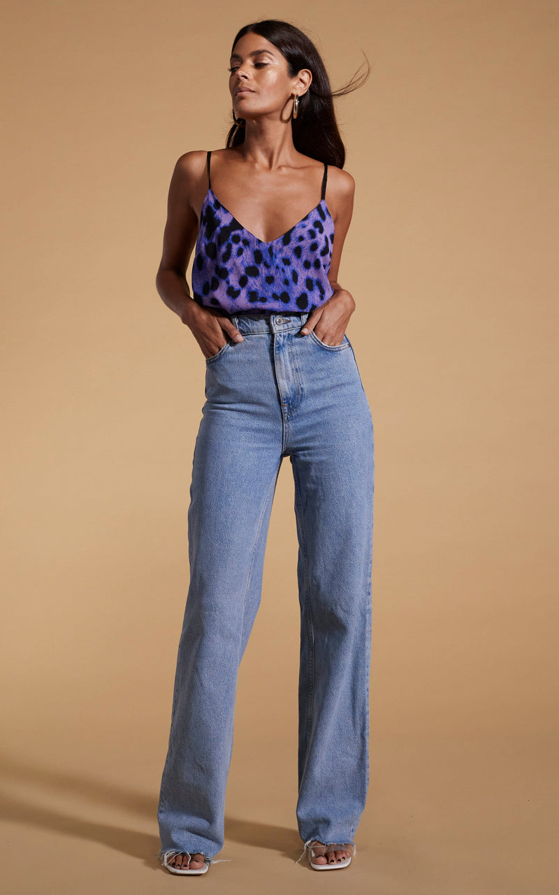 Dancing Leopard model wearing Birdie Cami Top in Lilac Leopard posed looking to the side with hands in jeans pockets
