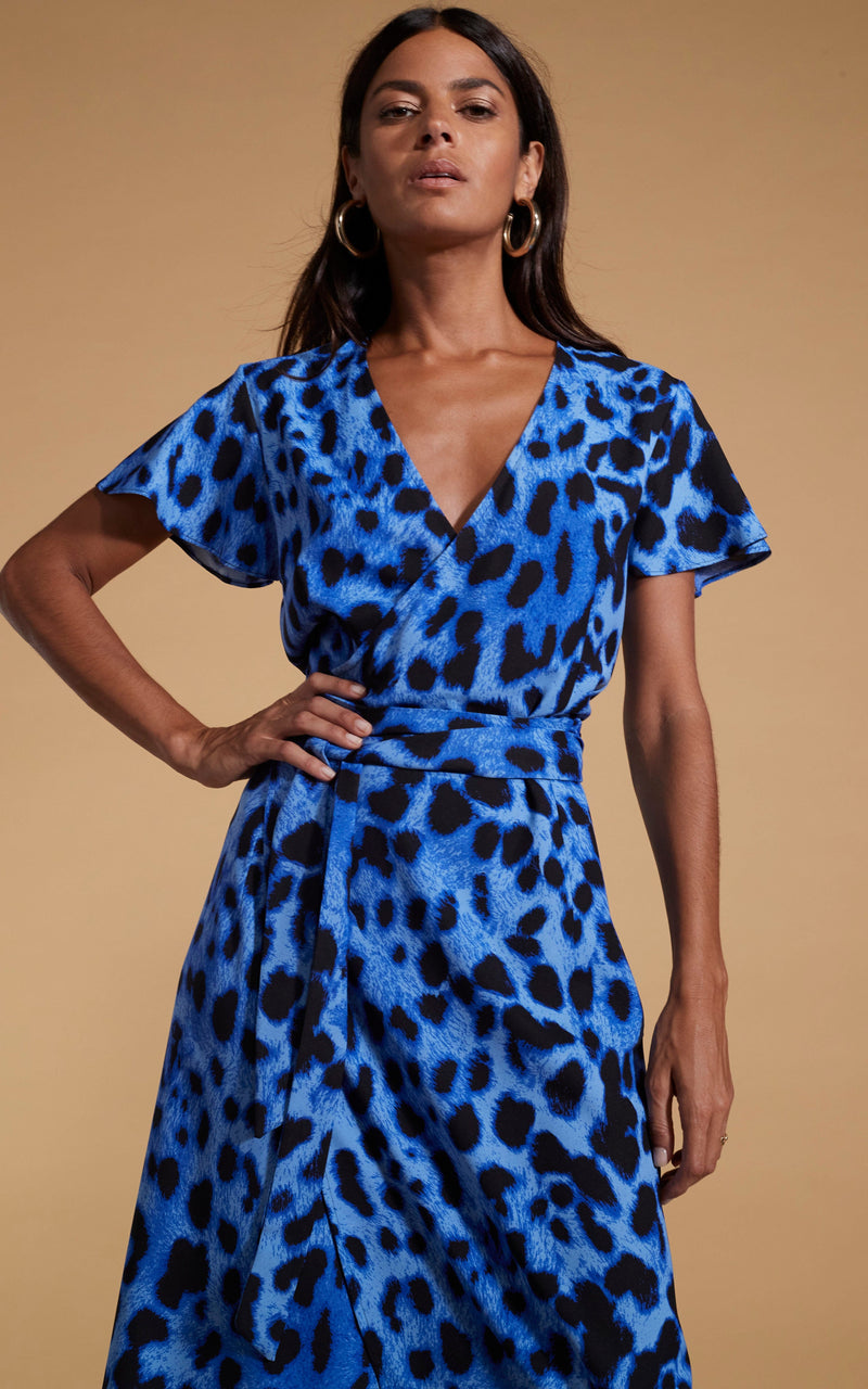 Dancing Leopard model wearing Cayenne Wrap Dress in Bright Blue Leopard posed with hand on hip