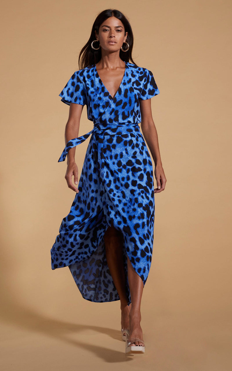 Dancing Leopard model wearing Cayenne Wrap Dress in Bright Blue Leopard walking towards shot