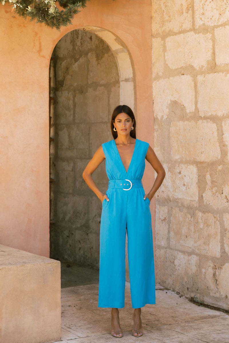 Dancing Leopard model posed in tall outdoor doorway wearing Indy Linen Jumpsuit In Blue - Reversible