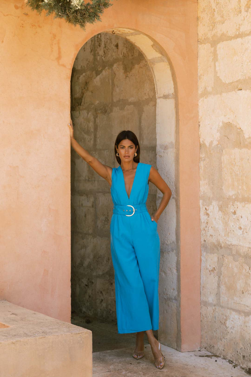 Dancing Leopard model stood against tall archway wearing Indy Linen Jumpsuit In Blue - Reversible