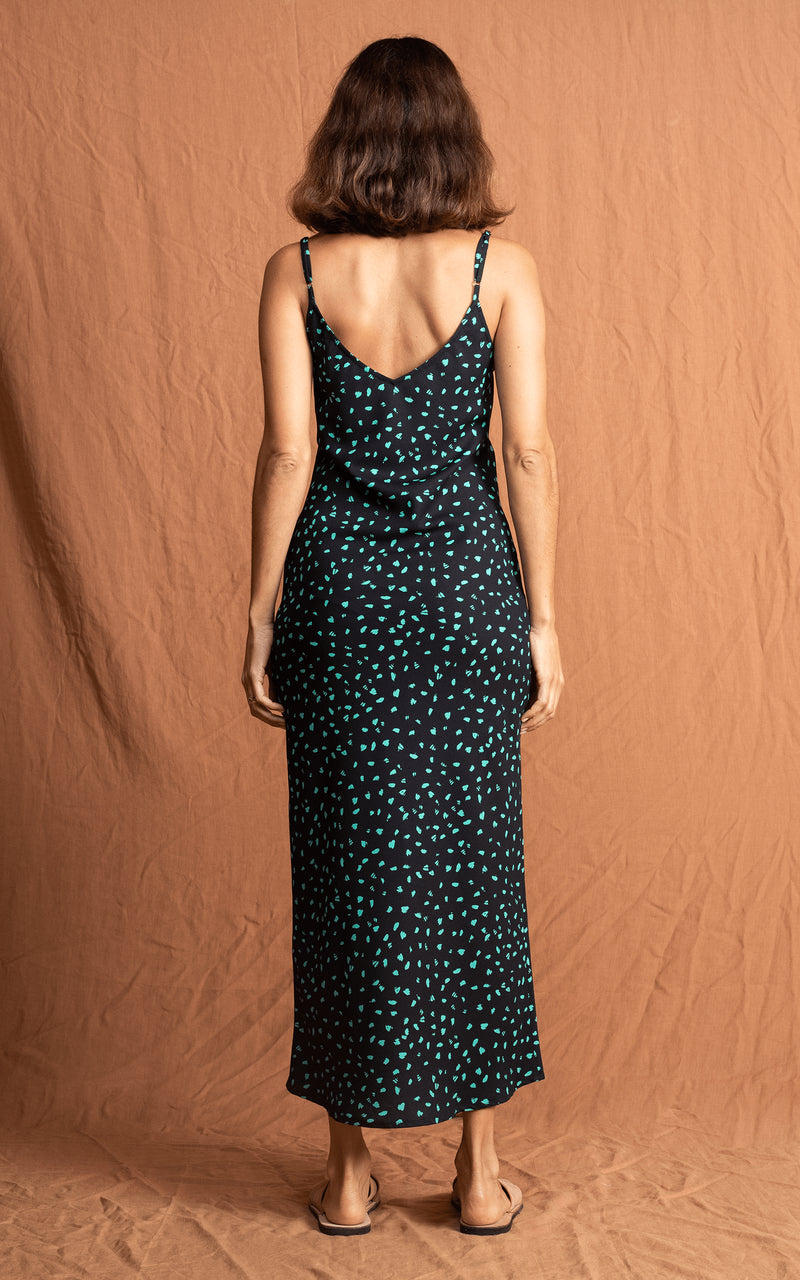 Dancing Leopard model faces backwards wearing Sienna Dress in green on black print with sandals