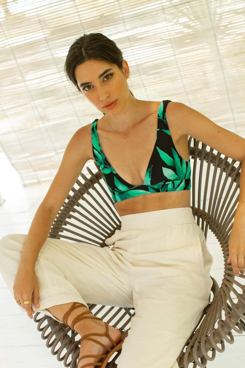 Dancing Leopard model sits on wicker chair wearing Tahiti Trousers with bikini top in tropical print