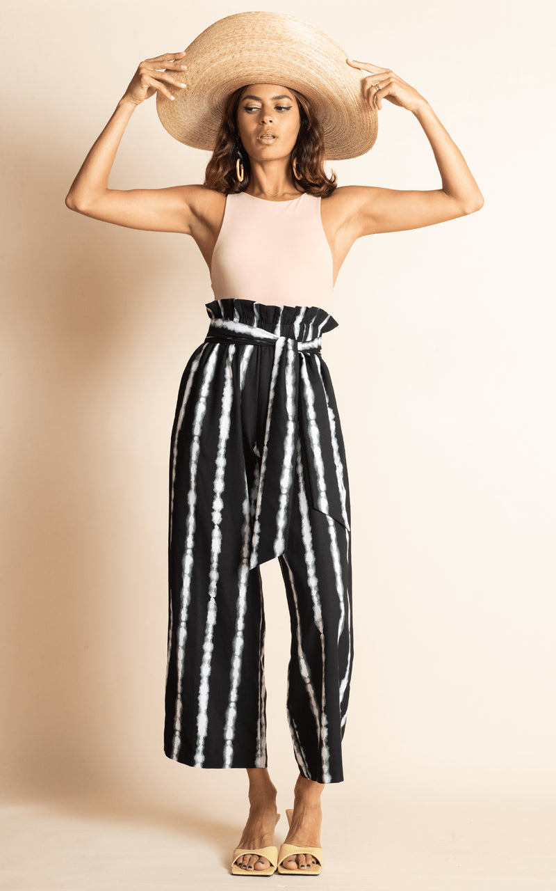 Dancing Leopard standing wearing black and white stripe winnie wide leg trousers with nude bodysuit and straw hat and sandals