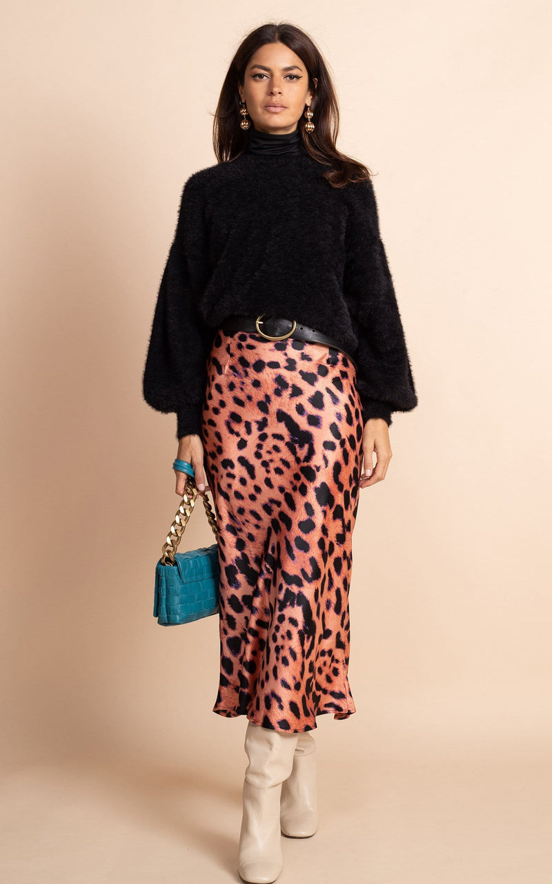 Dancing Leopard model wearing Renzo Skirt In Plorange Leopard with black jumper and green bag