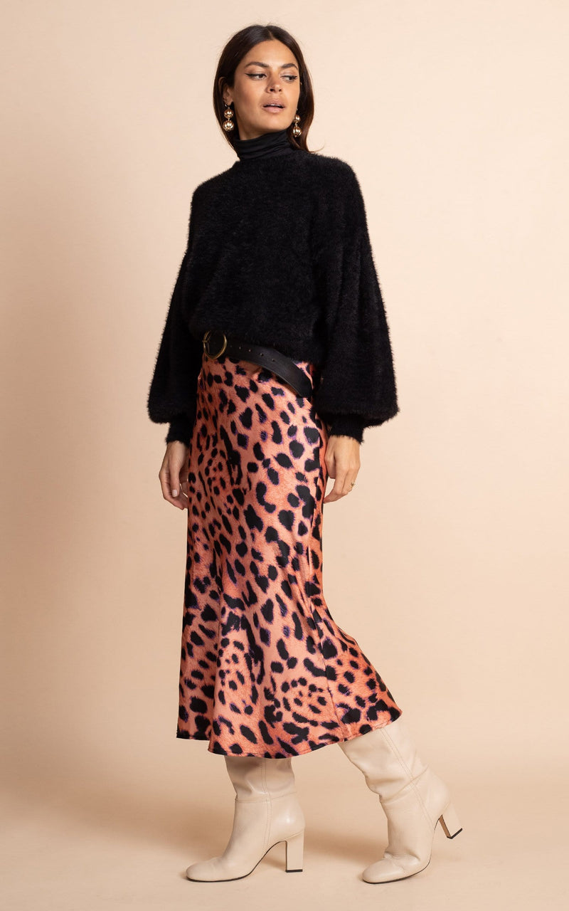 Dancing Leopard model wearing Renzo Skirt In Plorange Leopard with cream boots and black jumper facing side on