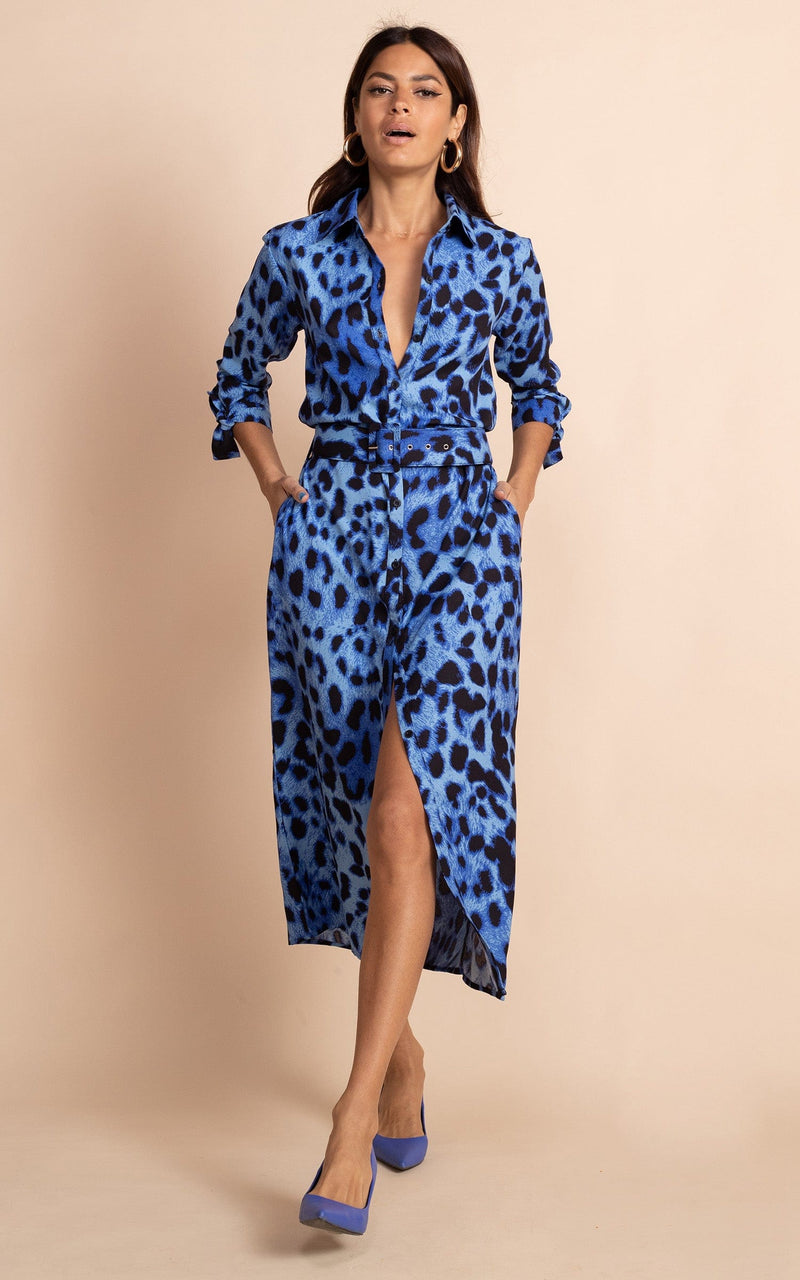 Dancing Leopard model standing face forward with hands in pockets wearing Alva midi shirt dress in bright blue leopard with blue heels